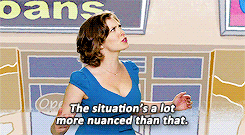 A woman with short brown hair in a blue dress gesturing with her hands and frowning as she says "The situation's a lot more nuanced than that." 